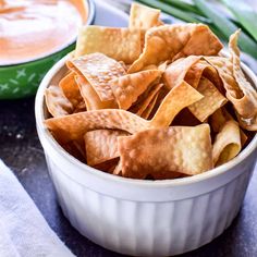 a bowl filled with tortilla chips next to another bowl full of dipping sauce