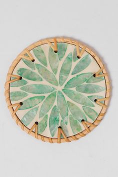 a plate with green leaves on it sitting on a white table top next to a wall