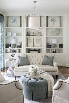 a living room with white furniture and blue accents