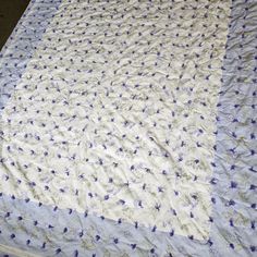 an unmade bedspread with blue flowers on it