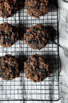 four cookies cooling on a wire rack with white paper behind them and one cookie in the middle