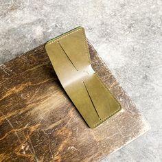 a leather wallet sitting on top of a wooden cutting board next to a knife blade