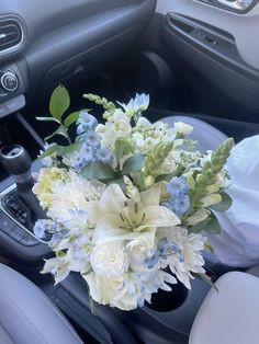 a bouquet of white and blue flowers in the center of a car's dashboard