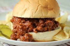 a sloppy joe sandwich on a plate with potato chips