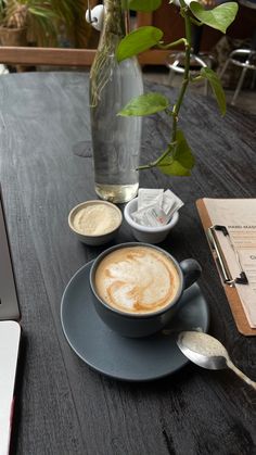 a cappuccino sits on a saucer next to a cup of coffee