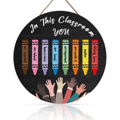 a wooden sign that says, in this classroom you are the crayons and hands