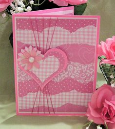 a close up of a card on a table with flowers and a vase in the background