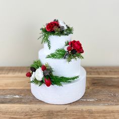 a three tiered white wedding cake decorated with red and white flowers