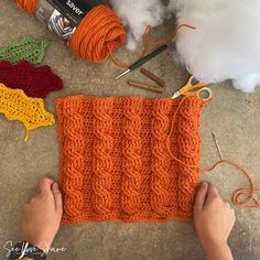 someone is crocheting on the ground with yarn, scissors and cotton in front of them