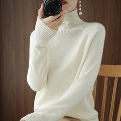 a woman is taking a selfie with her camera while wearing a white sweater and pearl earrings