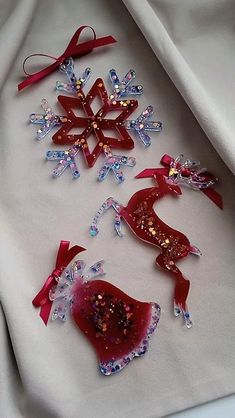 three snowflakes are sitting on a white cloth with red ribbons and bows