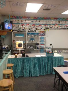 a classroom with tables, chairs and shelves full of books on the wall above them