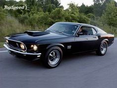 a black muscle car driving down the road