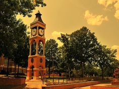 a clock tower in the middle of a park with benches and trees on either side