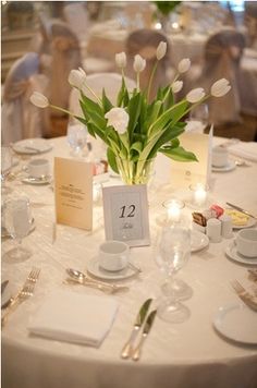 the table is set with white flowers and silverware