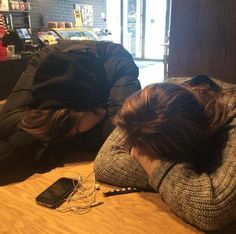 two people laying on the floor with their heads down and phones in front of them