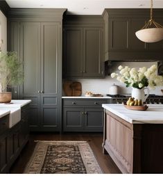 a kitchen with green cabinets and white counter tops, an area rug on the floor