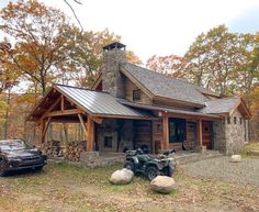 a car parked in front of a log cabin with a metal roof and two atvs