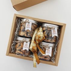 four jars of cookies in a box tied with a ribbon and sitting on top of a table