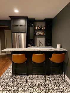 a kitchen with two bar stools next to an island in the middle of it