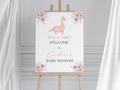 a baby shower sign on an easel with flowers and a giraffe in the background