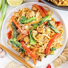 a white plate topped with noodles and veggies next to some chopsticks