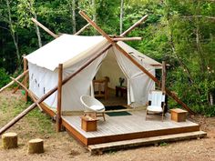 a tent set up in the woods with chairs