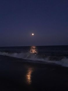 the moon is shining over the ocean at night