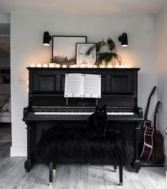 a black cat sitting on top of a bench next to a piano in a living room