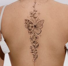 a woman's back tattoo with flowers and a butterfly on her left side ribcage