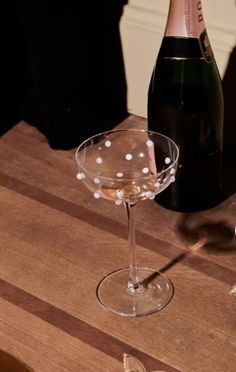 a wine glass and bottle sitting on a table next to each other with confetti in it