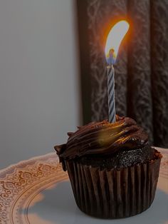 a chocolate cupcake with a single candle on it