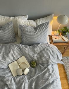 a bed with blue and white striped comforter next to a lamp on a nightstand