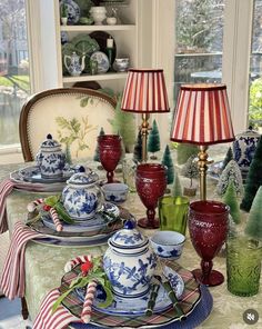 a dining room table set for christmas with red and white china, green glassware