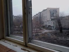 an open window looking out at a building and trees in the distance with no leaves on them