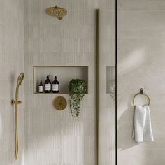 a white tiled bathroom with gold fixtures and shelves on the wall, along with a towel rack