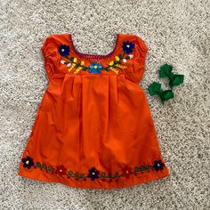 an orange dress laying on the floor next to a green toy