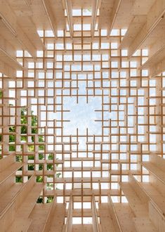 the inside of a wooden structure with lots of windows on each side and trees in the background