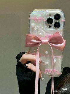 a person holding up a cell phone case with pink bows on it