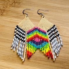 a pair of multicolored beaded earrings sitting on top of a wooden table