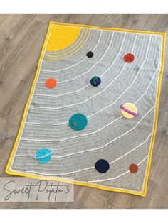 a crocheted rug with planets on it sitting on the floor in front of a wooden floor