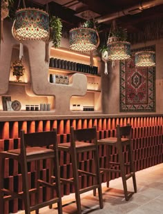 a bar with stools and hanging lights above it