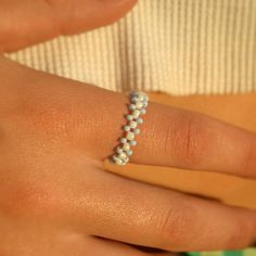 a close up of a person wearing a ring with pearls on it's fingers