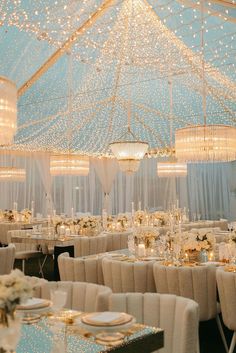 a banquet hall with tables, chairs and chandeliers covered in white draping