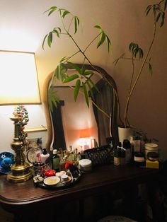 a mirror sitting on top of a wooden table next to a lamp and potted plant