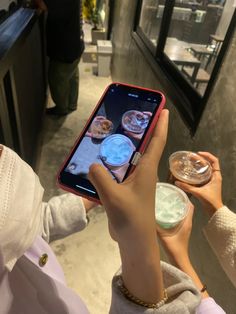 a person holding up a cell phone to take a photo with food in front of them