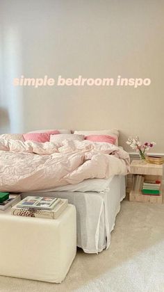 a bed with pink sheets and pillows in a bedroom next to a white foot stool