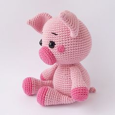 a pink crocheted stuffed animal sitting on top of a white surface with black eyes