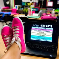 a person's feet resting on the keyboard of a laptop computer in a classroom