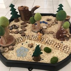 an indoor play area with rocks, logs and trees on the ground in front of a tiled floor